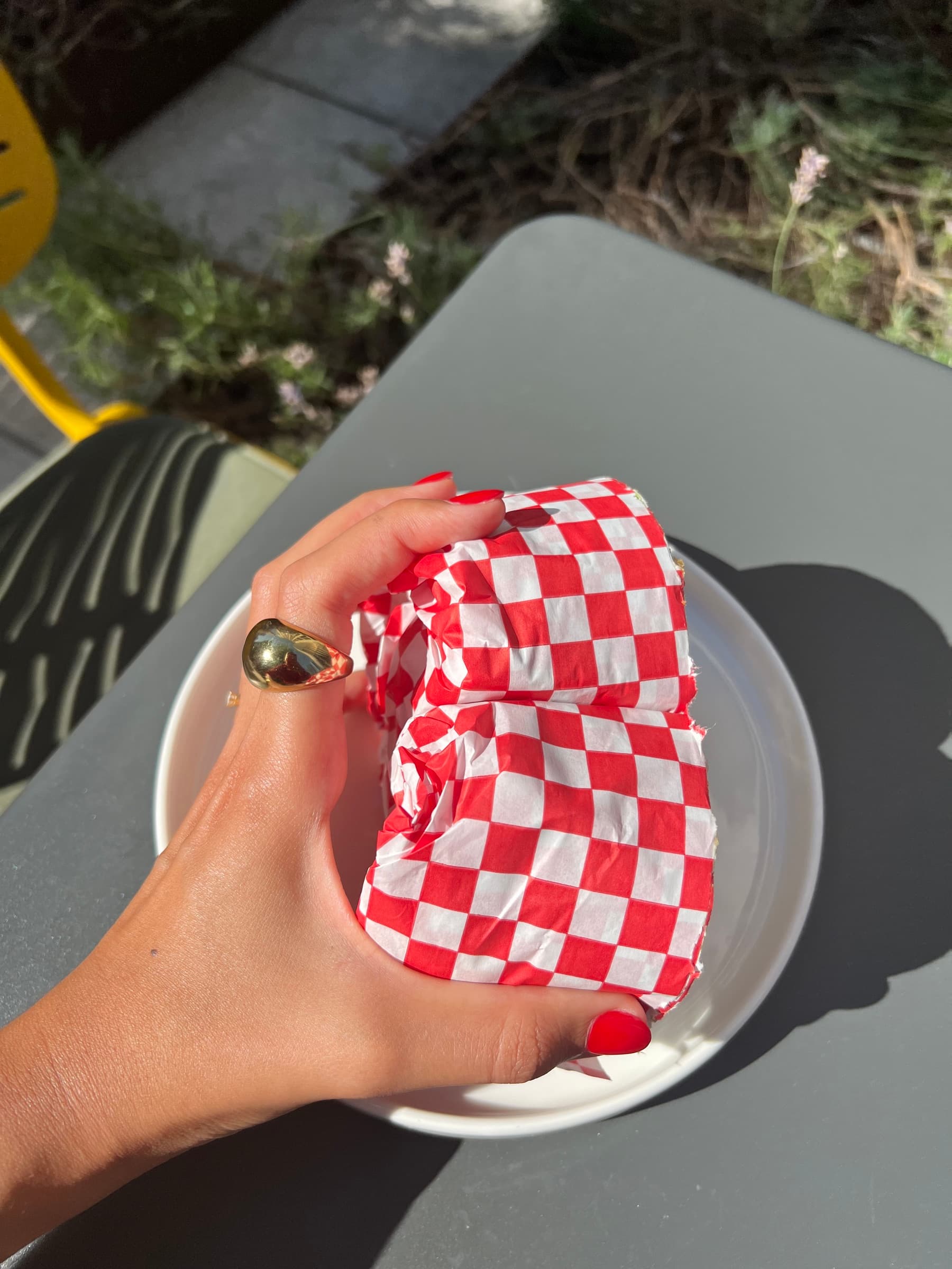 Hand hält ein Sandwich in kariertem Papier