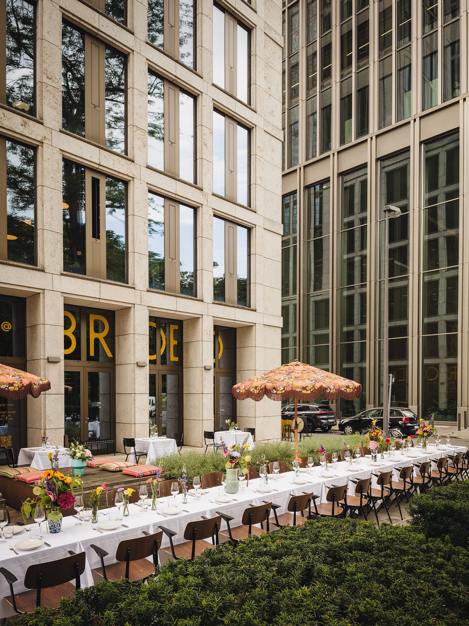 Lange Tafel mit Blumen vor der Fassade und den Hochhäusern