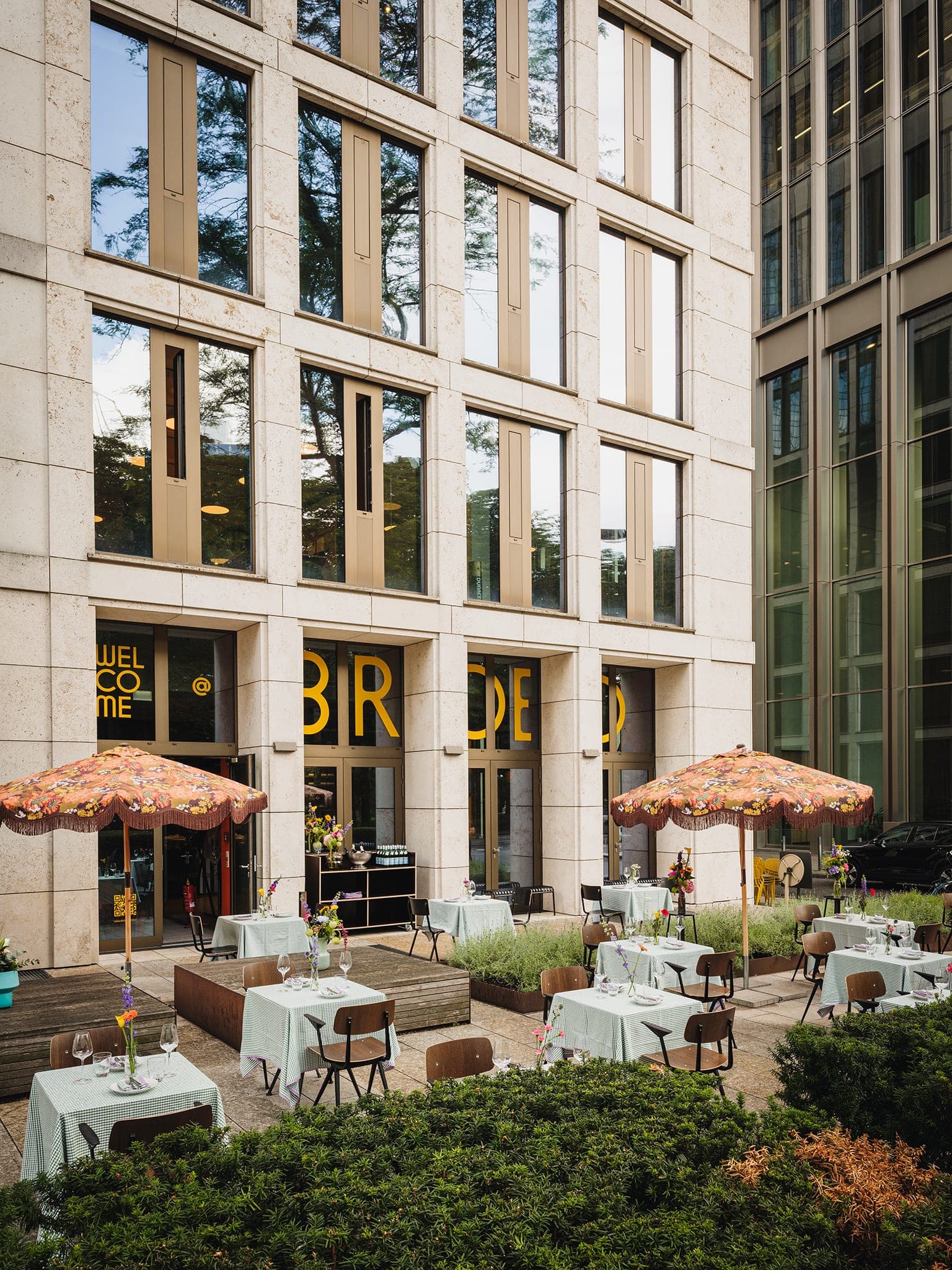 Terrasse vor der hohen Steinfassade mit dem BROED-Schriftzug